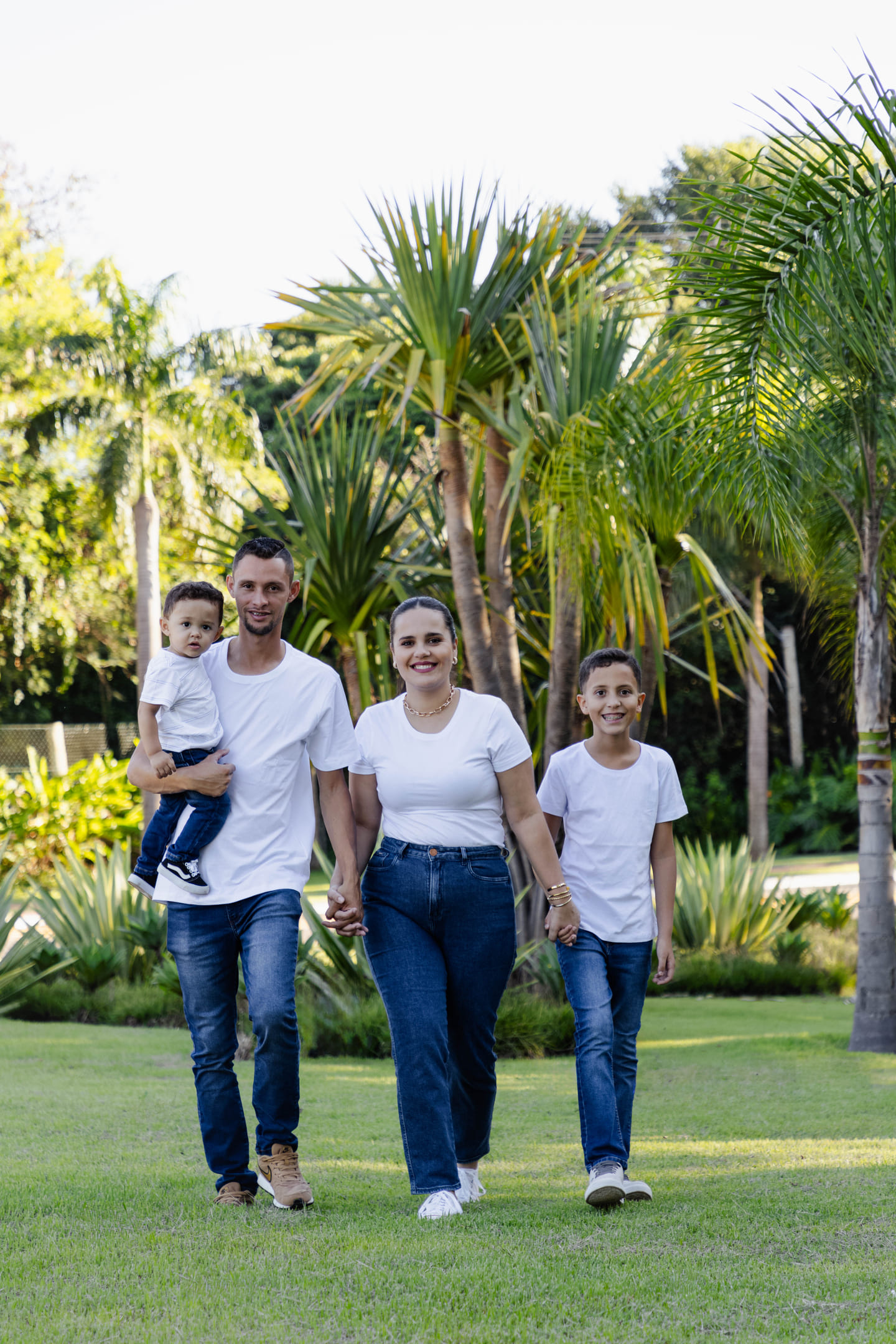 Família Géssica, Willian, Miguel e Théo caminhando juntos no gramado do Condomínio Forest Hill em Cianorte