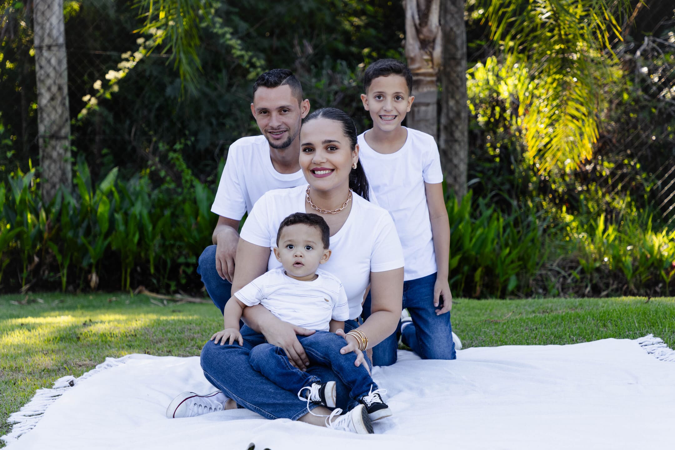 Géssica, Willian, Miguel e Théo sentados juntos no gramado do Condomínio Forest Hill em Cianorte