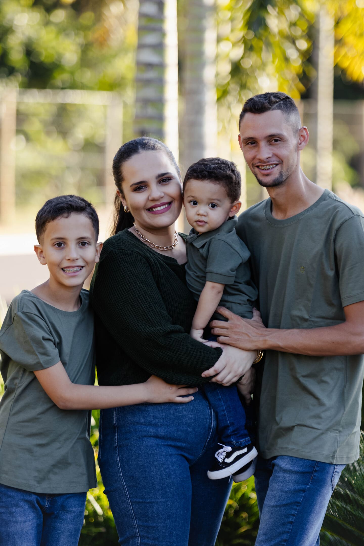 Retrato da família Géssica, Willian, Miguel e Théo com roupas verdes no Condomínio Forest Hill Cianorte
