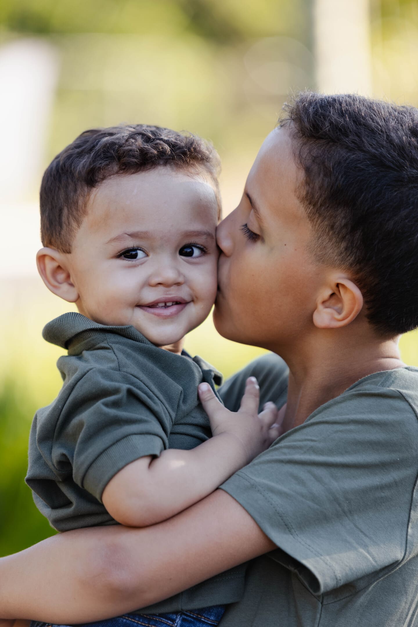 Miguel beijando o irmão Théo com carinho durante ensaio de família no Forest Hill Cianorte