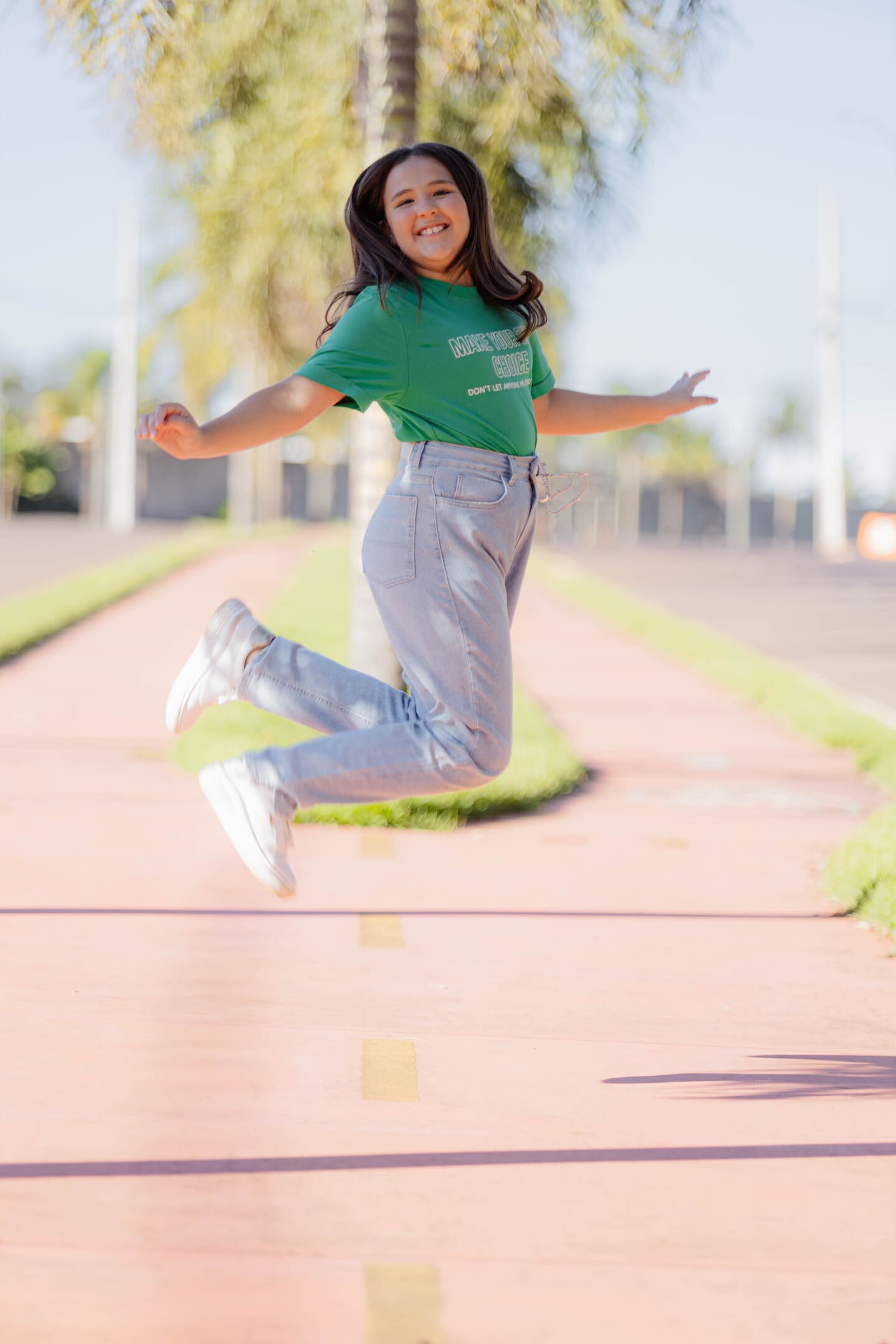 Maria Fernanda pulando de alegria no caminho do Condomínio Forest Hill durante ensaio de família