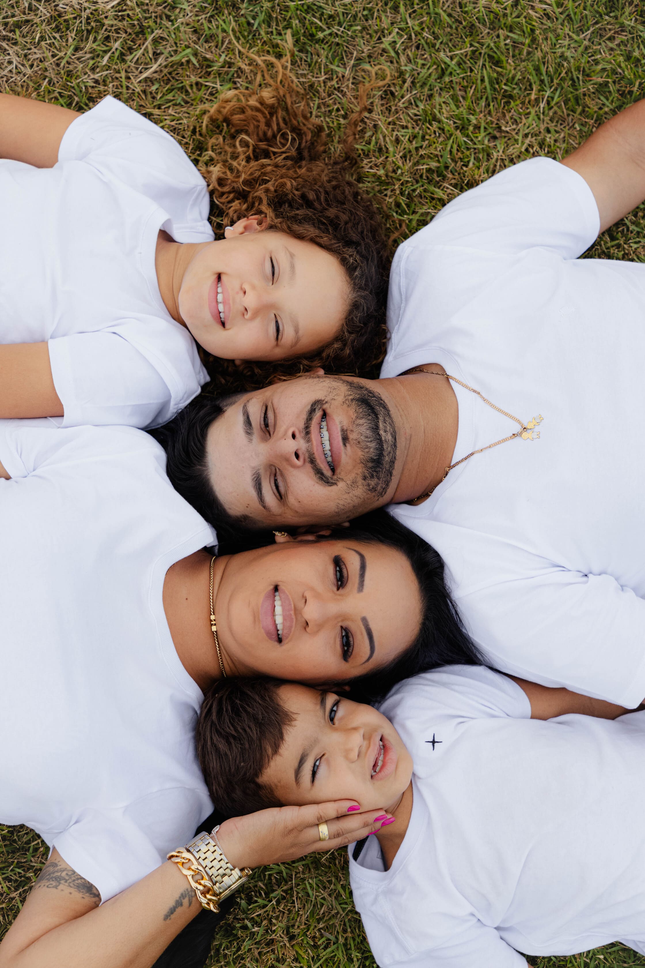 Família Wanessa Maximiliano Lorenzzo e Ana Laura deitados na grama sorrindo vista de cima