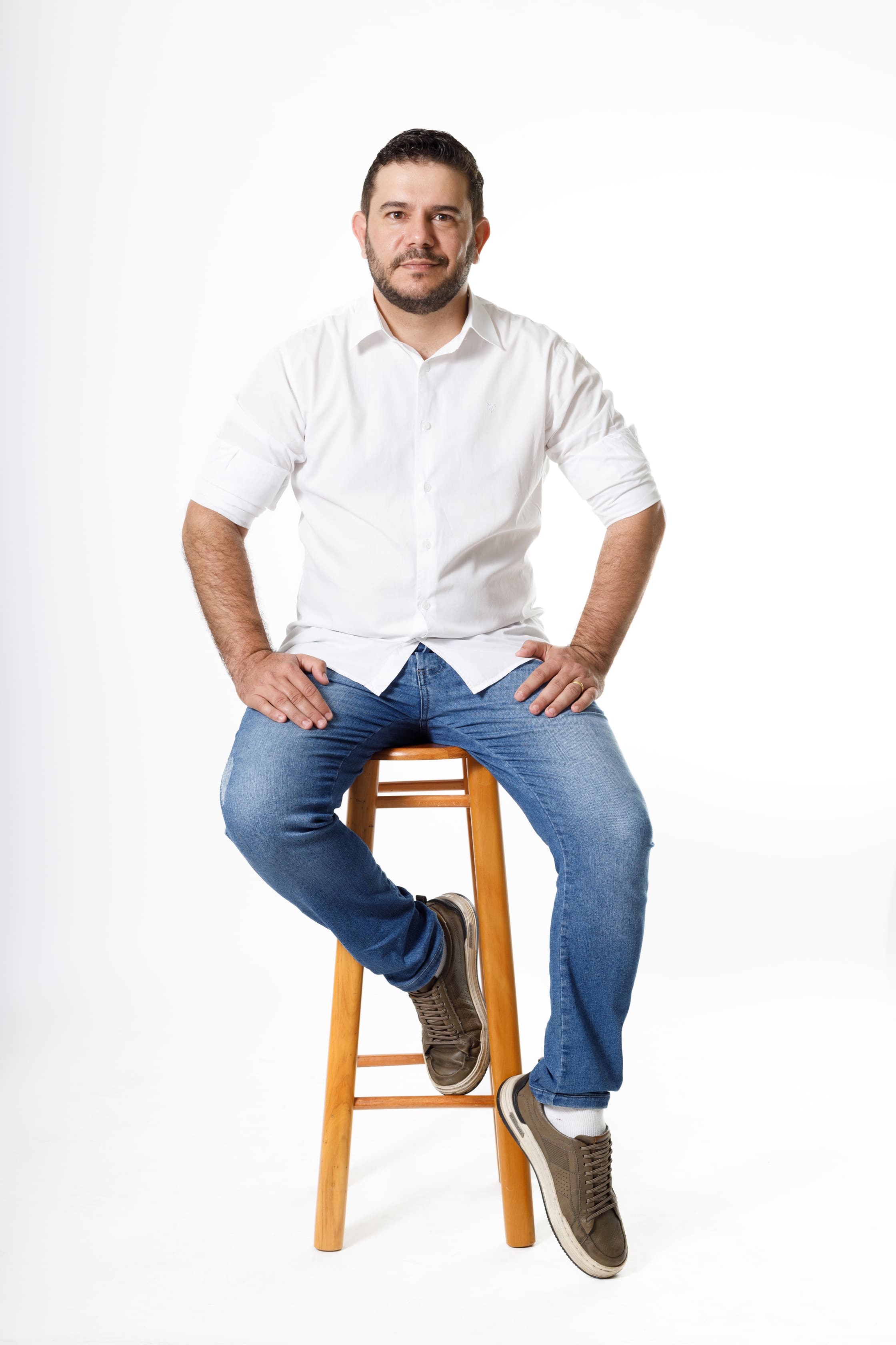 Casal Rodrigo Rezende e esposa em pé lado a lado sorrindo no Estúdio Foco de Cianorte com roupas brancas coordenadas