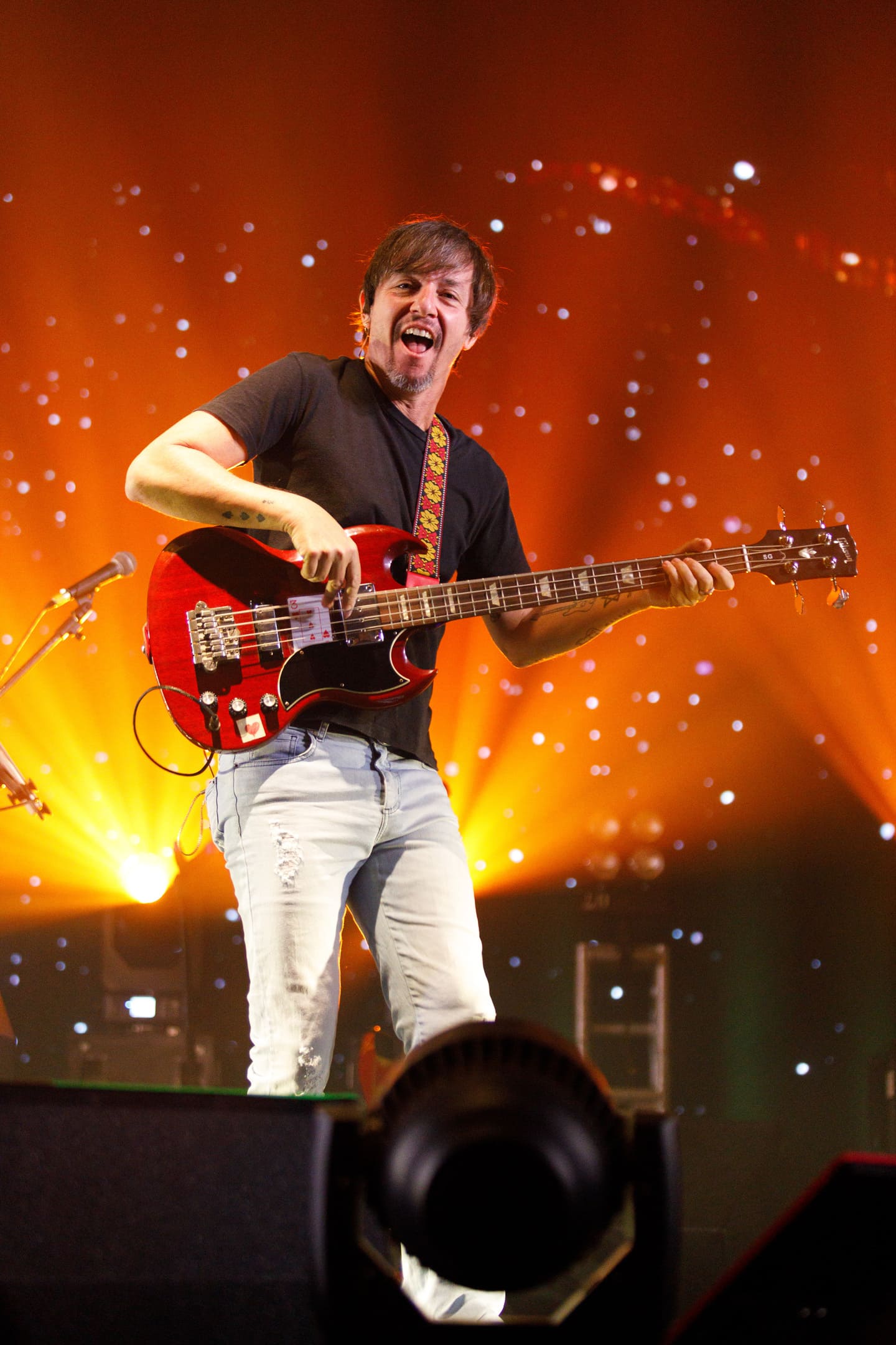 Baixista tocando contrabaixo vermelho no show As V Estações de Dado Villa-Lobos e Marcelo Bonfá em Maringá