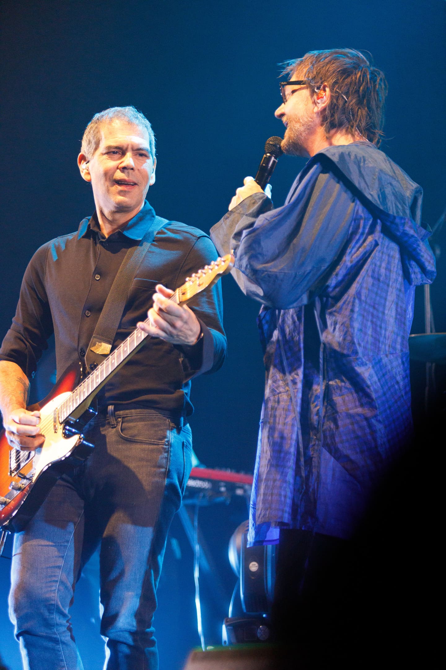 Dado Villa-Lobos e vocalista interagindo no palco durante show As V Estações na Paraná Expo