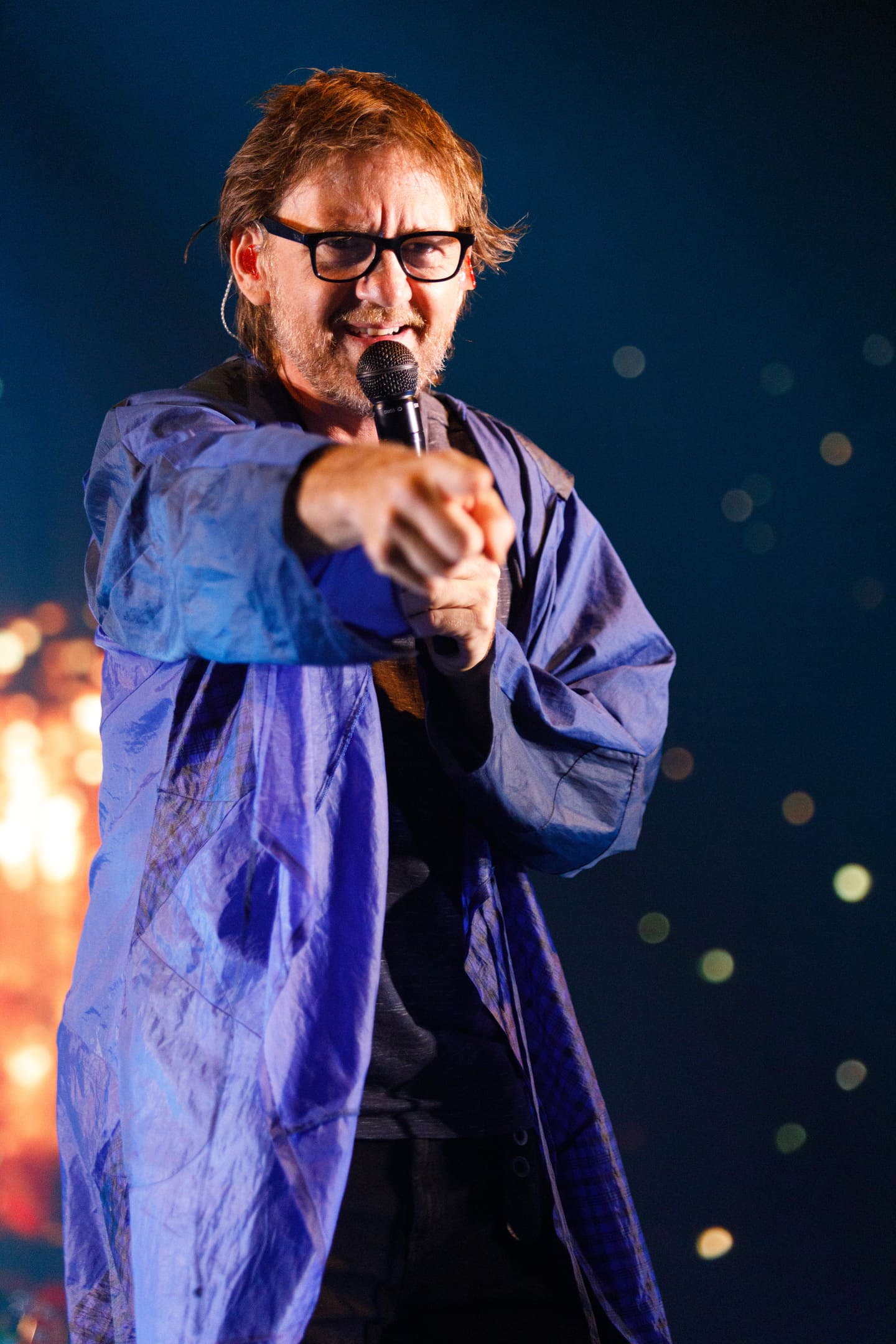Vocalista apontando para o público com microfone durante show As V Estações em Maringá