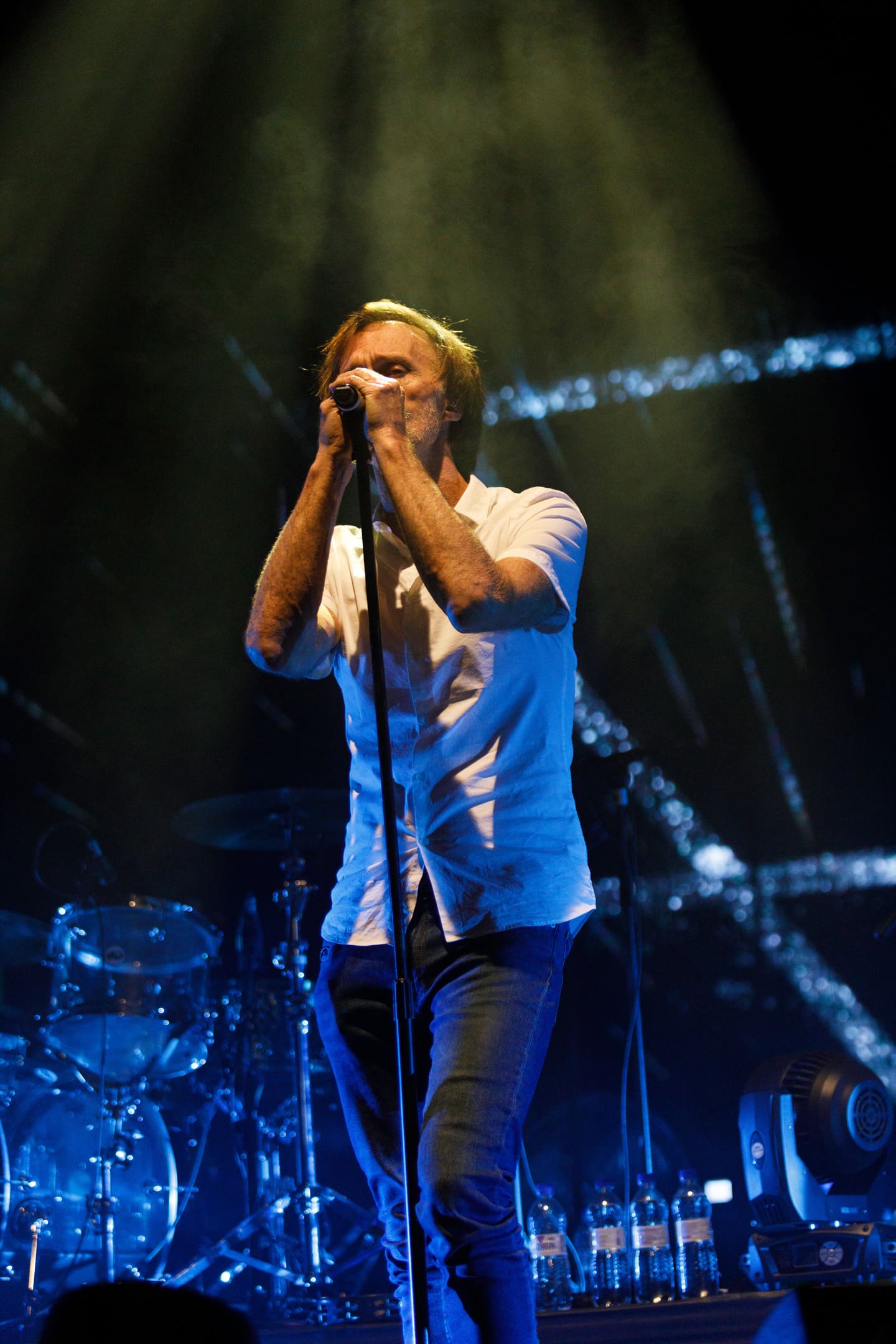 Marcelo Bonfá cantando ao microfone com camisa branca no show As V Estações em Maringá